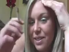 A white girl with golden hair blows large clouds of smoke in a sultry and playful manner.